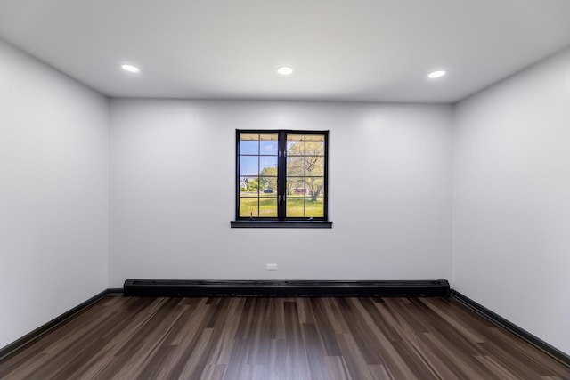 empty room with a baseboard heating unit, recessed lighting, dark wood-style flooring, and baseboards