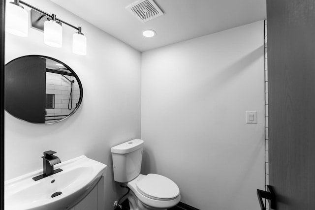 bathroom with toilet, a sink, and visible vents