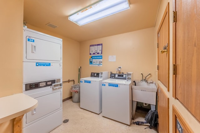 community laundry room with washing machine and dryer, a sink, visible vents, light floors, and stacked washer and clothes dryer