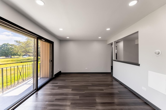 empty room with dark wood-type flooring, recessed lighting, and baseboards