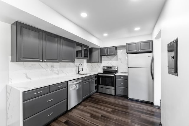 kitchen with tasteful backsplash, appliances with stainless steel finishes, dark wood-style flooring, gray cabinetry, and a sink