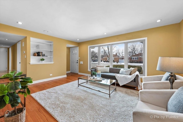 living area with built in shelves, light wood-type flooring, baseboards, and recessed lighting