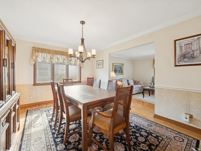 dining space featuring baseboards, light wood-style flooring, a chandelier, and crown molding