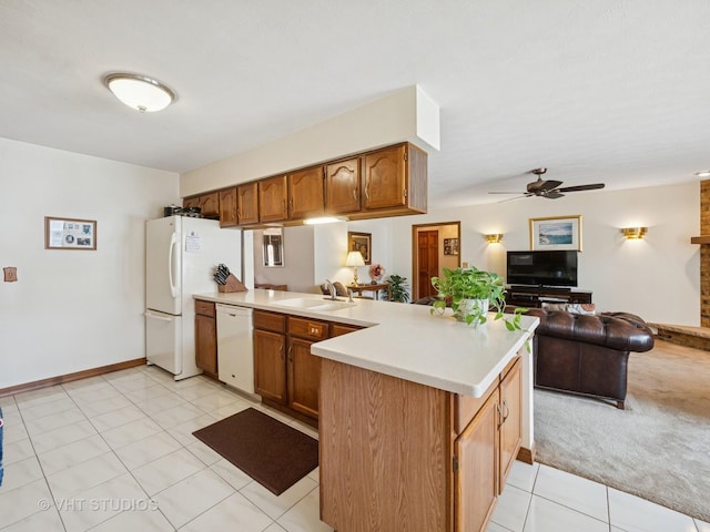 kitchen with white appliances, light countertops, a sink, and a peninsula