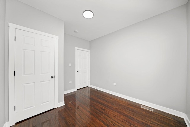 unfurnished bedroom featuring dark wood-type flooring, visible vents, and baseboards