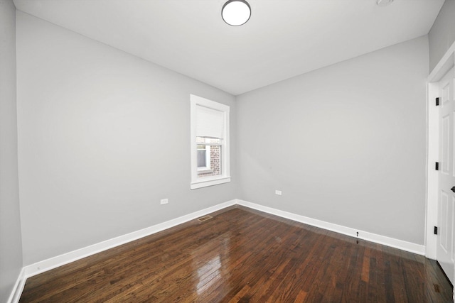 unfurnished room featuring visible vents, baseboards, and dark wood-style flooring