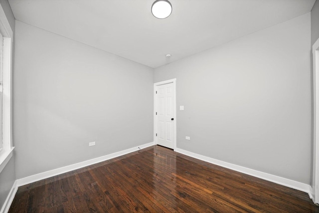 spare room with baseboards and wood finished floors