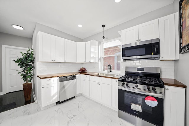 kitchen featuring wooden counters, appliances with stainless steel finishes, a sink, and pendant lighting