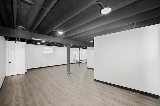 below grade area featuring a sink, baseboards, and wood finished floors