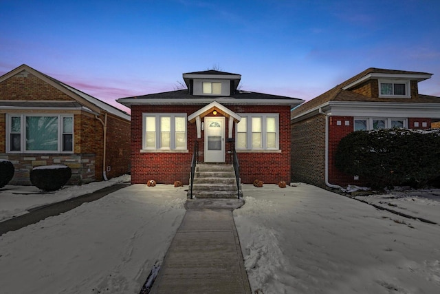 bungalow featuring brick siding