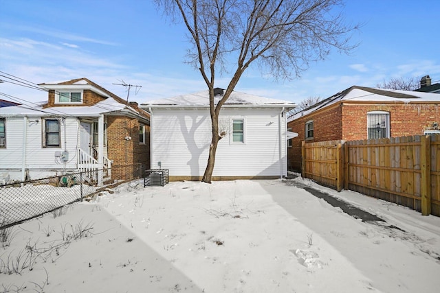 snow covered house featuring fence and central AC