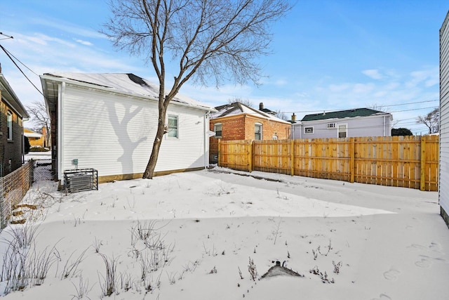 snow covered back of property featuring fence