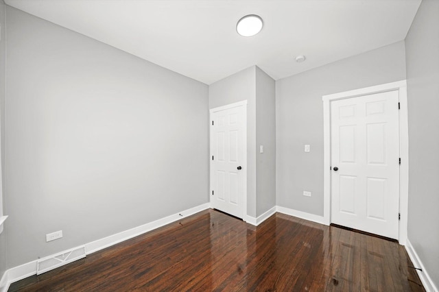 unfurnished bedroom with visible vents, dark wood finished floors, and baseboards