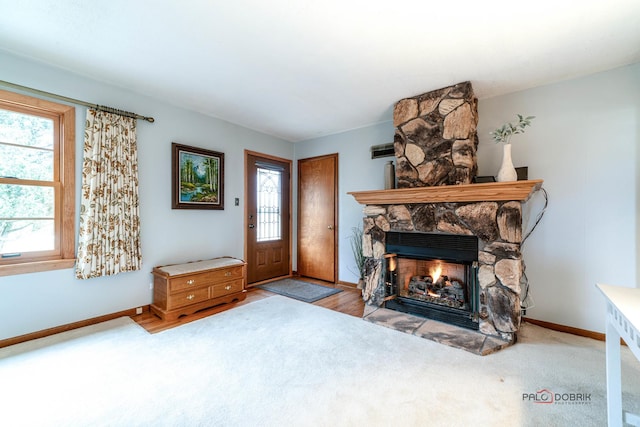 foyer entrance featuring light colored carpet, a fireplace, and baseboards