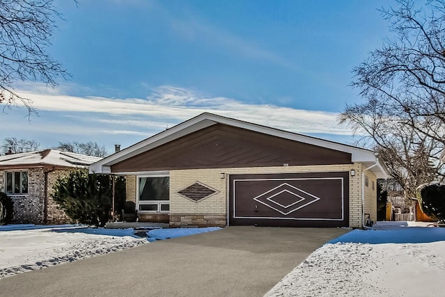 view of front facade featuring driveway, an attached garage, and brick siding