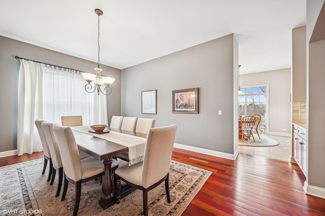 dining room with dark wood-style floors, baseboards, and an inviting chandelier