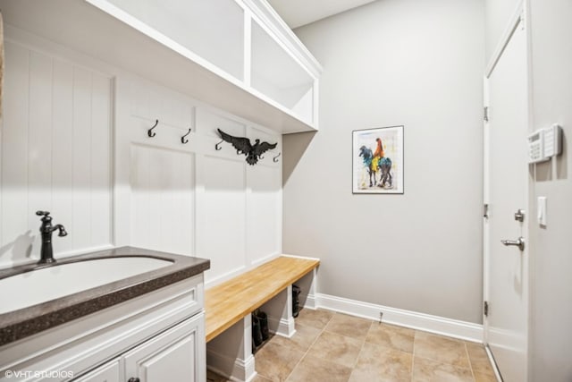 mudroom with light tile patterned flooring, a sink, and baseboards