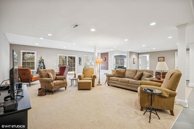 living area featuring ornate columns, visible vents, light colored carpet, and recessed lighting