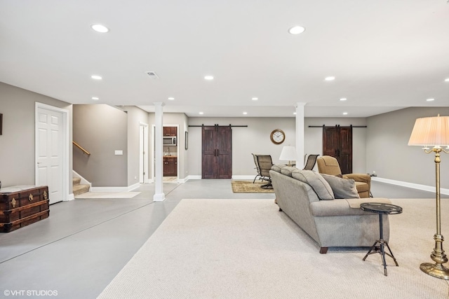 living room with finished concrete flooring, a barn door, stairs, and recessed lighting