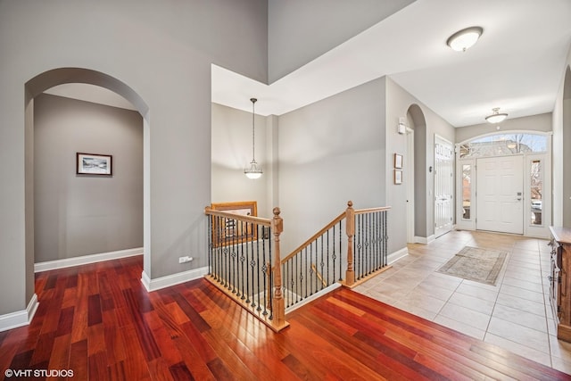 entrance foyer with arched walkways, wood finished floors, and baseboards