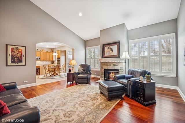 living room featuring arched walkways, dark wood finished floors, and baseboards