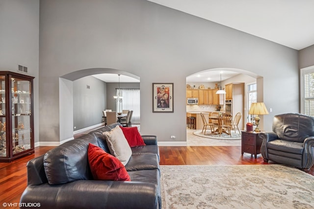 living room featuring arched walkways, wood finished floors, visible vents, and baseboards