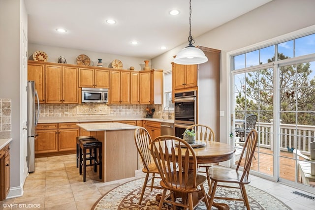 kitchen with a sink, a kitchen island, visible vents, light countertops, and appliances with stainless steel finishes