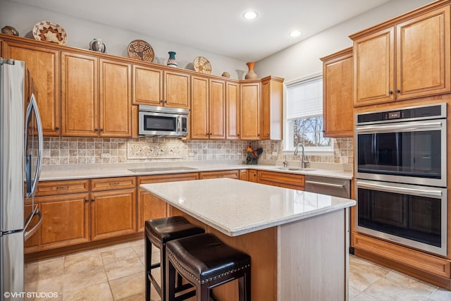 kitchen featuring appliances with stainless steel finishes, a kitchen breakfast bar, a center island, a sink, and backsplash