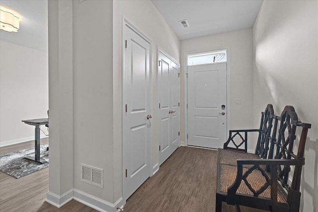 entryway with dark wood finished floors, visible vents, and baseboards