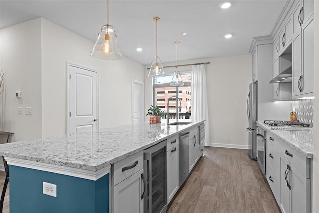 kitchen with beverage cooler, dark wood finished floors, appliances with stainless steel finishes, wall chimney range hood, and a sink