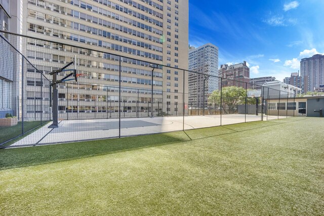 surrounding community featuring community basketball court, fence, and a city view