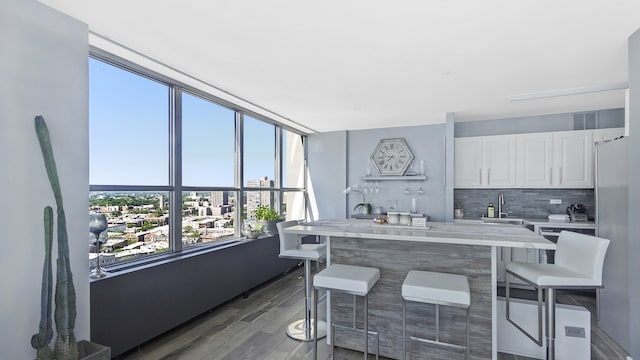 kitchen featuring a breakfast bar area, white cabinetry, light countertops, backsplash, and dark wood-style floors