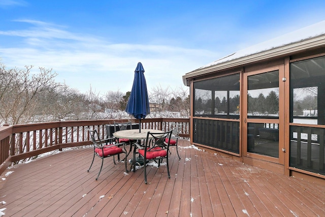 snow covered deck with a sunroom and outdoor dining area