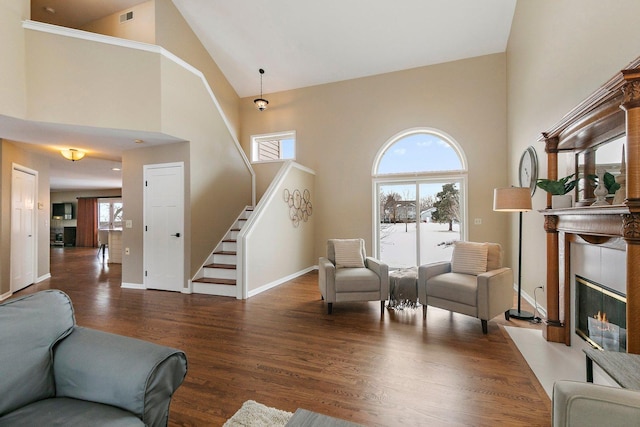 living area featuring a fireplace with flush hearth, visible vents, baseboards, stairway, and dark wood-style floors