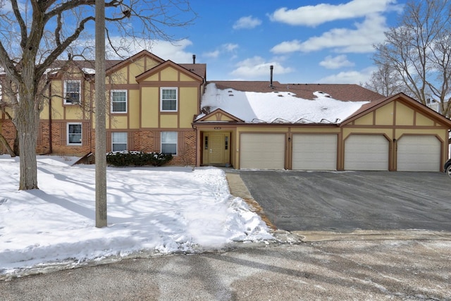 tudor house featuring aphalt driveway, brick siding, and stucco siding