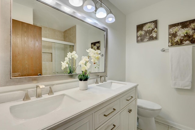 bathroom featuring double vanity, toilet, a sink, and a shower with shower door