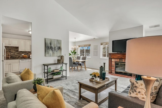 living area featuring a notable chandelier, visible vents, a brick fireplace, light carpet, and high vaulted ceiling