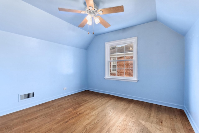 bonus room featuring light wood-style floors, baseboards, visible vents, and vaulted ceiling