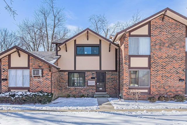 view of front of house featuring an AC wall unit, brick siding, and stucco siding