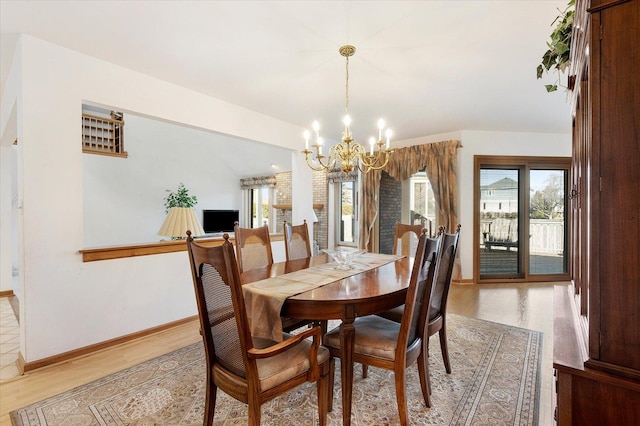 dining space featuring baseboards, a notable chandelier, and light wood finished floors