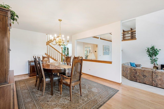 dining room featuring an inviting chandelier, stairway, baseboards, and wood finished floors