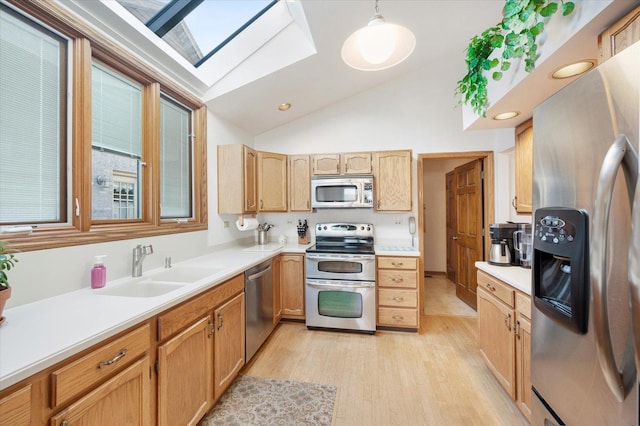 kitchen with appliances with stainless steel finishes, vaulted ceiling with skylight, light countertops, and a sink