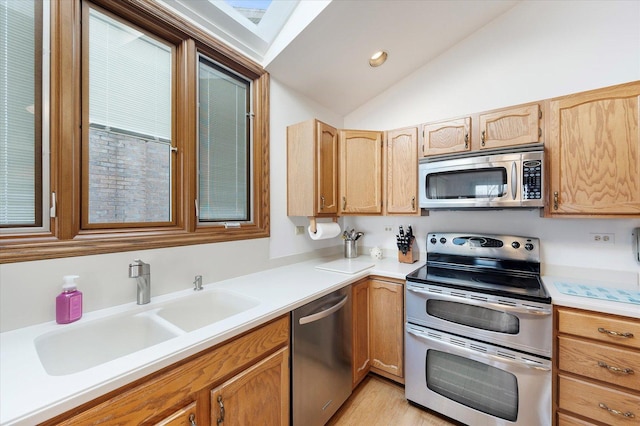 kitchen with lofted ceiling, light wood-style flooring, stainless steel appliances, light countertops, and a sink