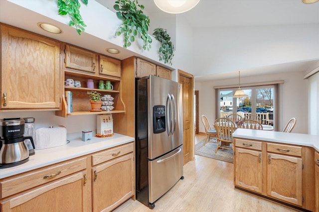 kitchen with decorative light fixtures, stainless steel refrigerator with ice dispenser, open shelves, light countertops, and light wood-type flooring