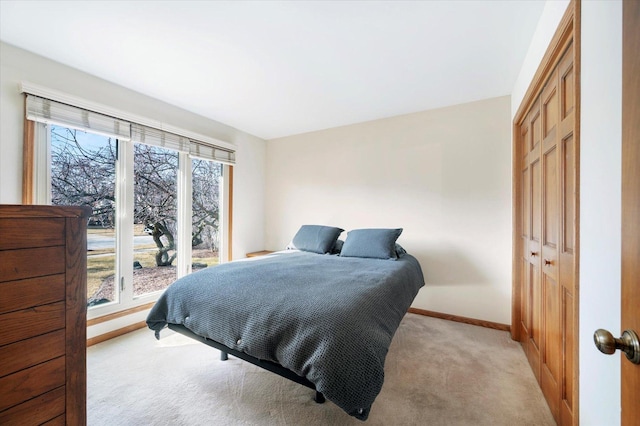 bedroom featuring light carpet, a closet, and baseboards