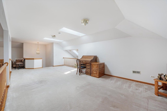 carpeted home office featuring vaulted ceiling with skylight, visible vents, and baseboards