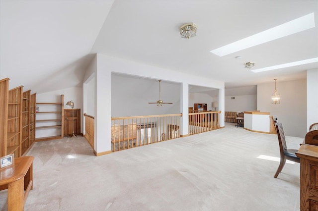 interior space featuring lofted ceiling with skylight, light colored carpet, and ceiling fan