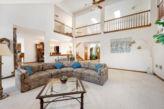 living room with ceiling fan with notable chandelier, carpet floors, visible vents, baseboards, and stairs