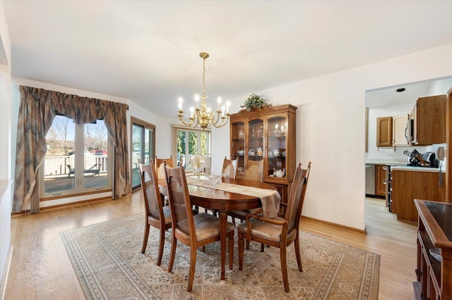 dining room with light wood-style floors, baseboards, and a chandelier