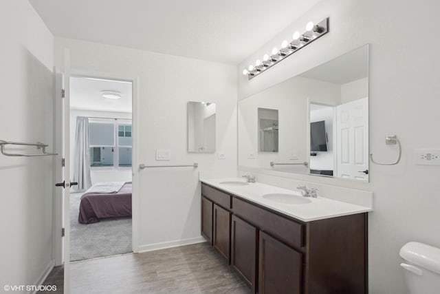 full bathroom featuring connected bathroom, a sink, toilet, and double vanity